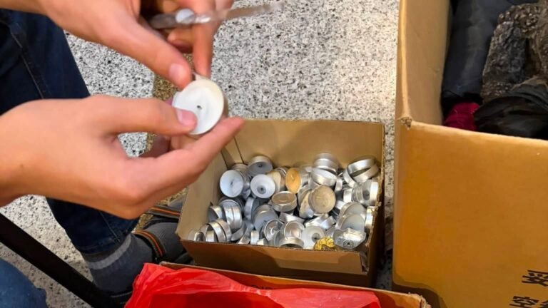 Rankos laiko išdegusią skridininę žvakę virš dėžių su aliuminio indeliais – apkasų žvakių sezono pradžia Kaune