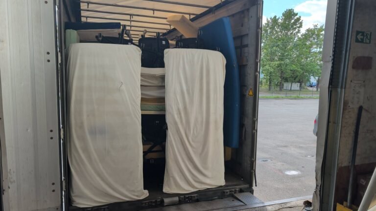 Į sunkvežimį pakrauti ligoninės čiužiniai ir lovos, matomi pro atvirą kėbulo galą