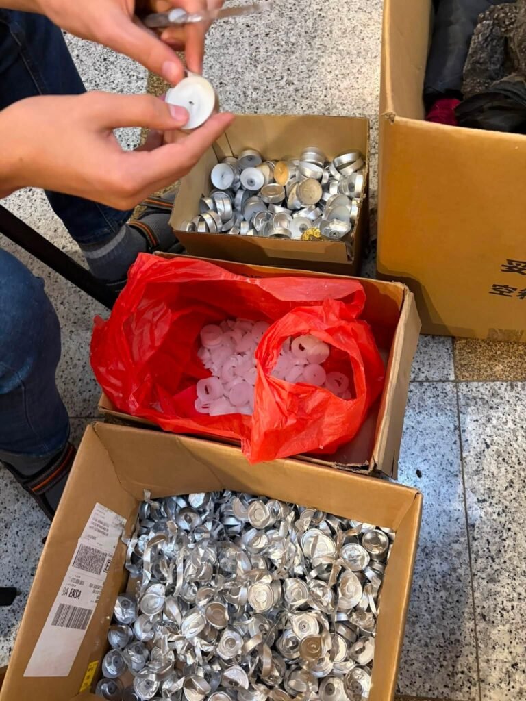 Savanoris rankose laiko išdegusią skridininę žvakę; dėžės su tuščiais aliuminio indeliais ir maišas parafino likučių