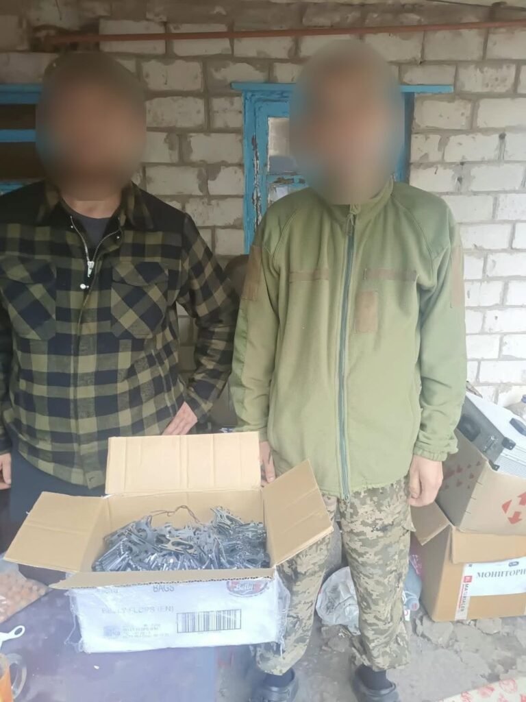 Du 93-iosios brigados kariai prie atidarytos dėžės su metalinėmis tvirtinimo detalėmis; veidai uždengti
