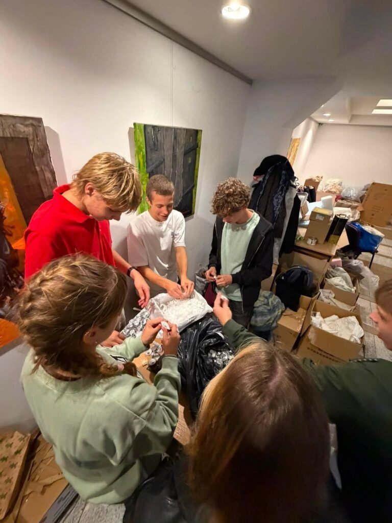Jaunųjų konservatorių lygos jaunimas prie stalo lukštena bažnytines žvakeles, atskirdamas parafiną nuo aliuminio