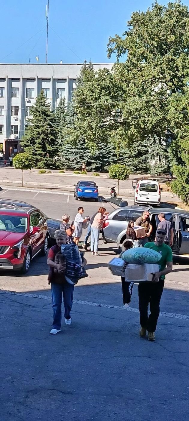 Savanoriai neša dėžes ir ryšulius su parama nuo automobilių Pyriatyno aikštėje