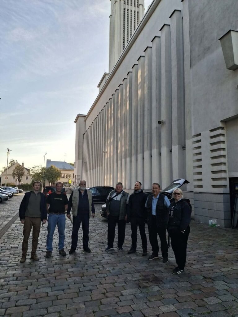 Septyni savanoriai vairuotojai stovi ant grindinio prie Kauno Kristaus Prisikėlimo bazilikos ankstų rytą prieš išvažiuodami į Ukrainą